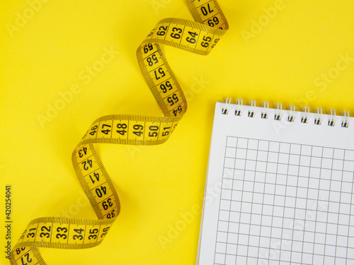 Yellow tape measure centimetric with paper note on yellow background