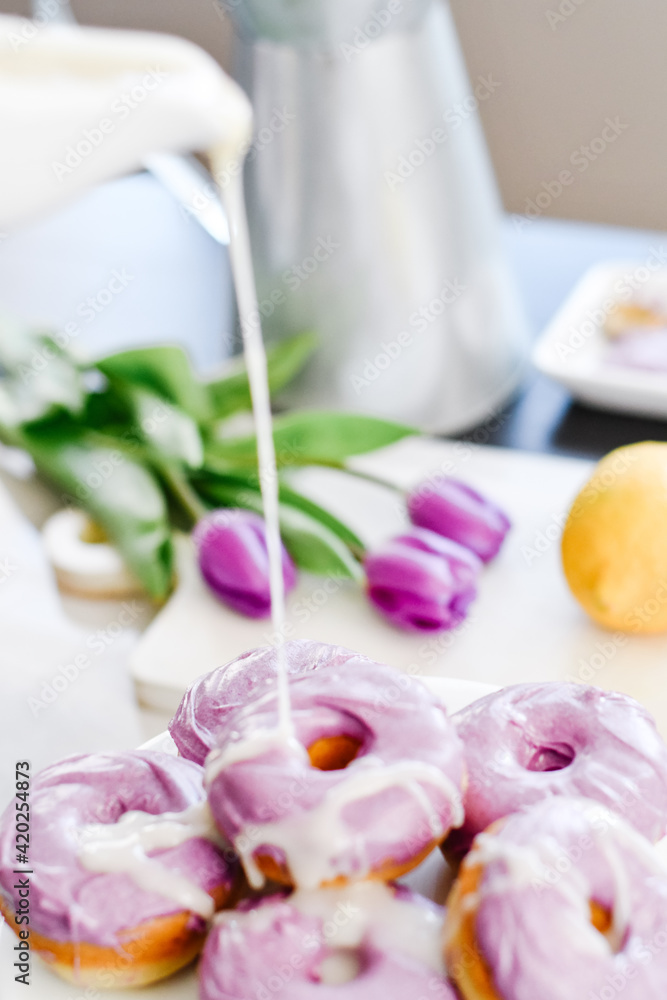 Homemade Purple donuts on dessert stand with Spring flowers Homemade Purple donuts on dessert stand with Spring flowers