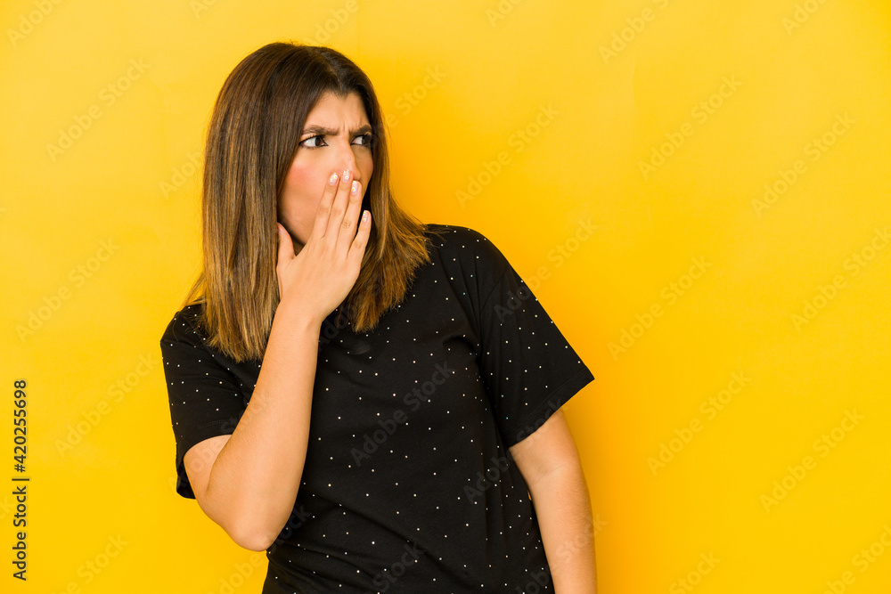 Young indian woman isolated on yellow background being shocked because of something she has seen. Young indian woman isolated on yellow background being shocked because of something she has seen.