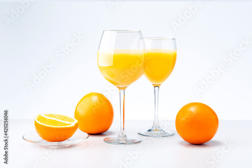 Two glasses of orange juice and fruits on light grey background. Healthy food and drink concept.