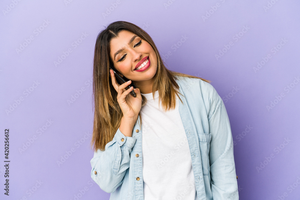 Young indian woman holding a phone isolated showing a mobile phone call gesture with fingers. Young indian woman holding a phone isolated showing a mobile phone call gesture with fingers.