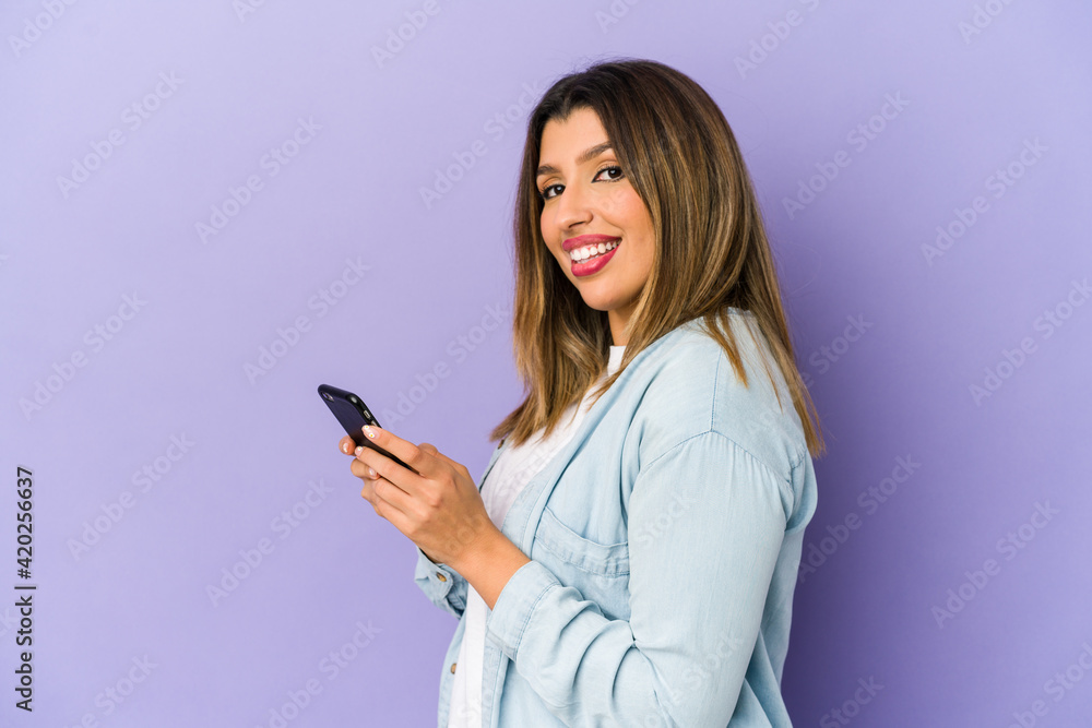 Young indian woman holding a phone isolated looks aside smiling, cheerful and pleasant. Young indian woman holding a phone isolated looks aside smiling, cheerful and pleasant.