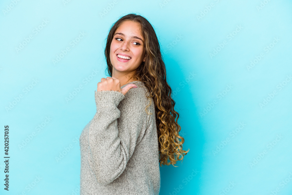 Young caucasian curly hair woman isolated points with thumb finger away, laughing and carefree. Young caucasian curly hair woman isolated points with thumb finger away, laughing and carefree.