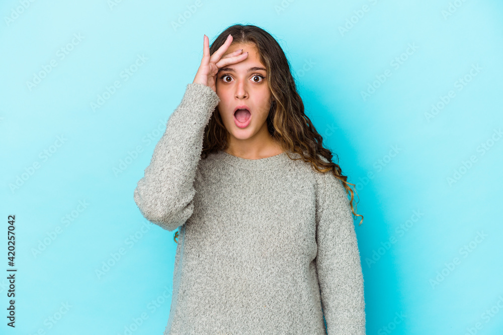 Young caucasian curly hair woman isolated shouts loud, keeps eyes opened and hands tense. Young caucasian curly hair woman isolated shouts loud, keeps eyes opened and hands tense.