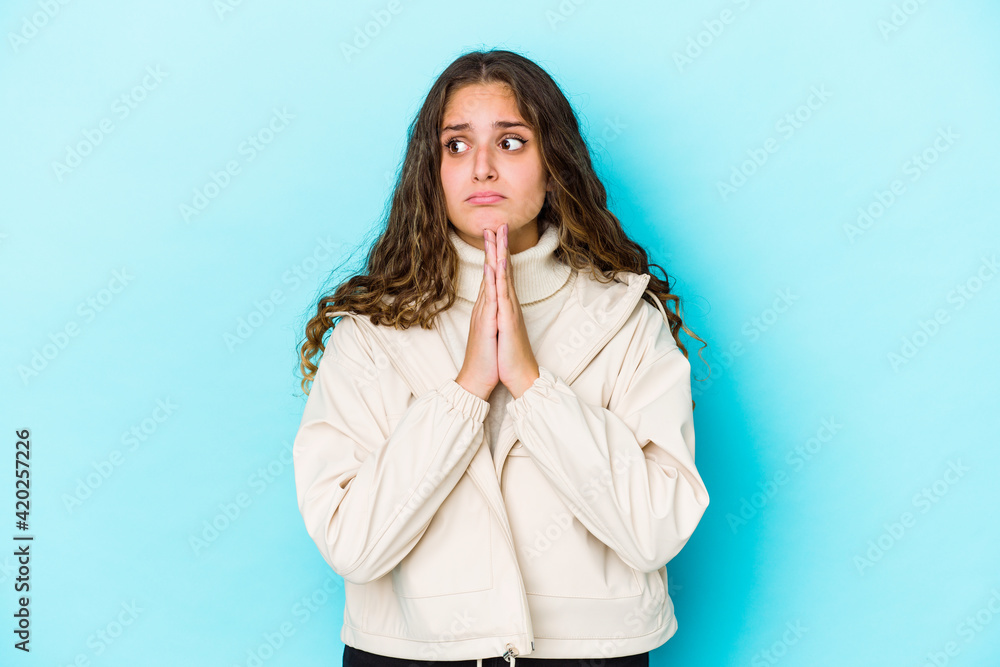 Young caucasian curly hair woman isolated praying, showing devotion, religious person looking for divine inspiration. Young caucasian curly hair woman isolated praying, showing devotion, religious person looking for divine inspiration.