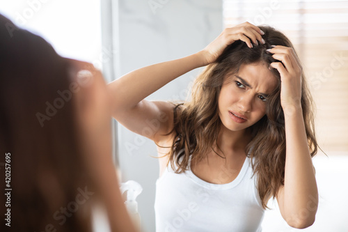 Unhappy Woman Looking At Hair Flakes Having Dandruff Problem Indoor photo
