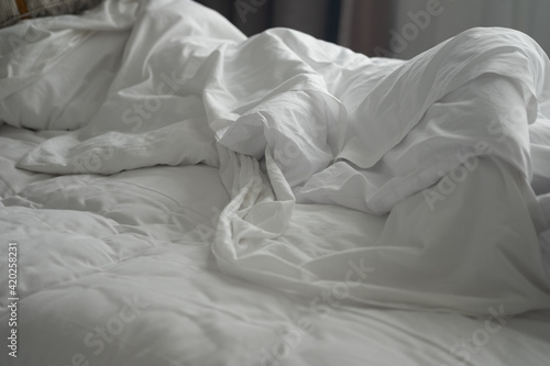 White pillow with blanket on bed unmade