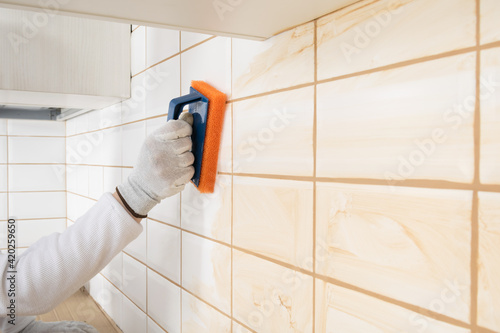 Fotografie a ceramic tile laying master wipes the seams with a special sponge