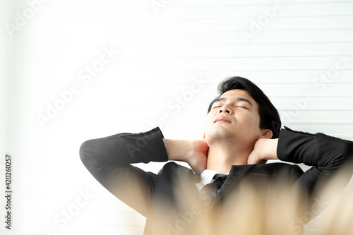 Portrait exhausted businessman in black suite disappointed or failing at the office. He try relaxing with hands behind head. Having break at office concept.