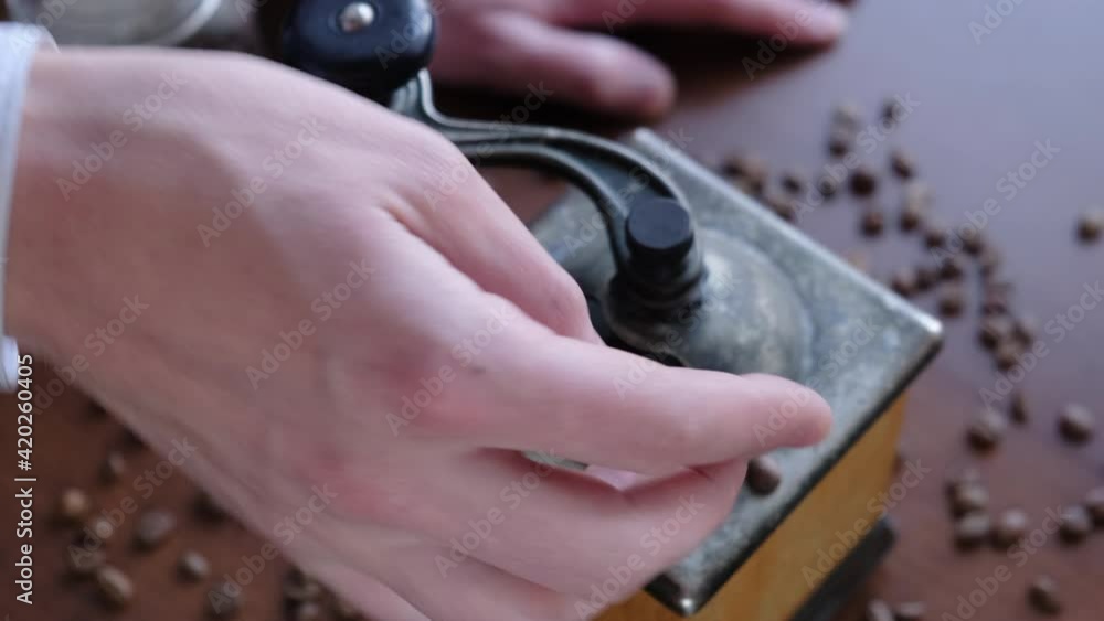 A man pours coffee beans into a coffee grinder, closeup A man pours coffee beans into a coffee grinder, closeup