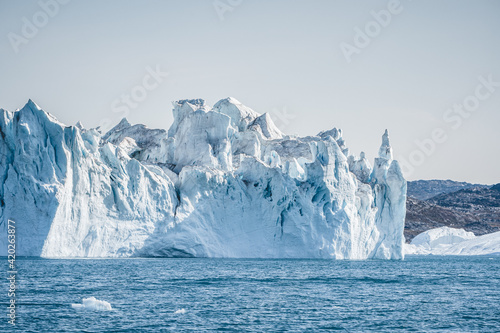 Bright sunny day in Antarctica. Full calm and reflection of icebergs in deep clear water. Travel by the ship among ices. Snow and ices of the Antarctic islands.