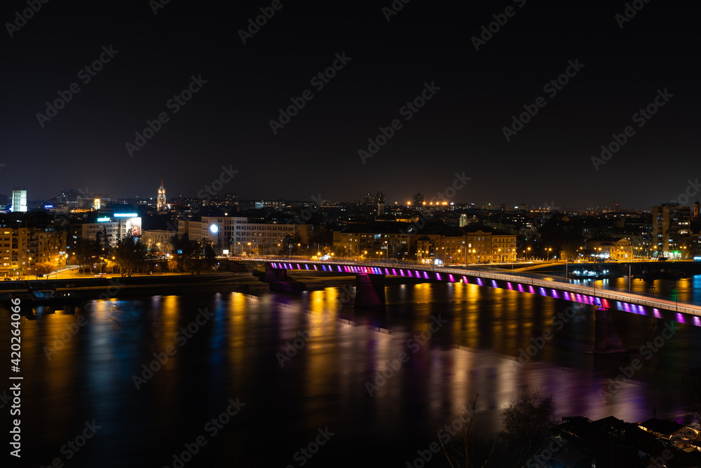 Night panoramic view of Novi Sad, Serbia cityscape with bridges, Danube river and Petrovaradin fortress with beautiful colorful street lights from the town