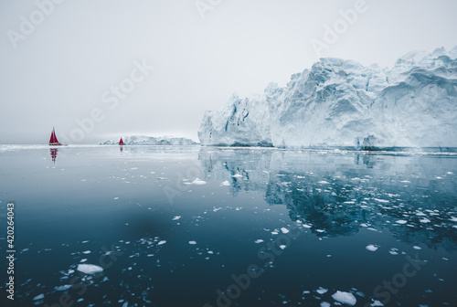 Arctic nature landscape with icebergs in Greenland icefjord with midnight sun sunset sunrise in the horizon. Early morning summer alpenglow during midnight season. Ilulissat, West Greenland.