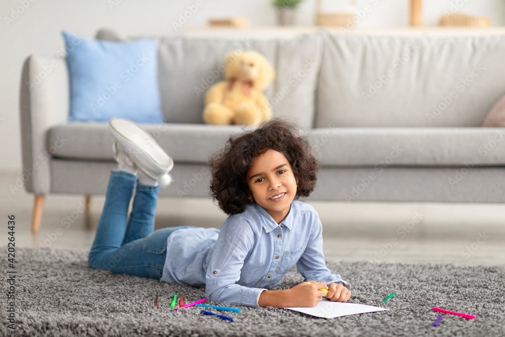 African American girl drawing on paper with colorful crayons African American girl drawing on paper with colorful crayons