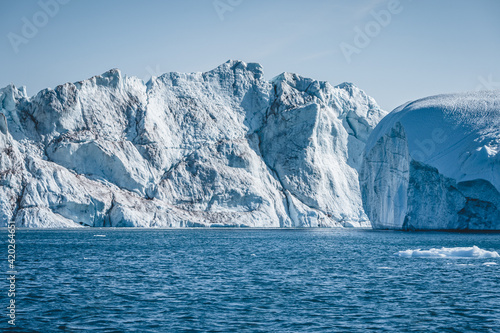 Bright sunny day in Antarctica. Full calm and reflection of icebergs in deep clear water. Travel by the ship among ices. Snow and ices of the Antarctic islands. © Mathias