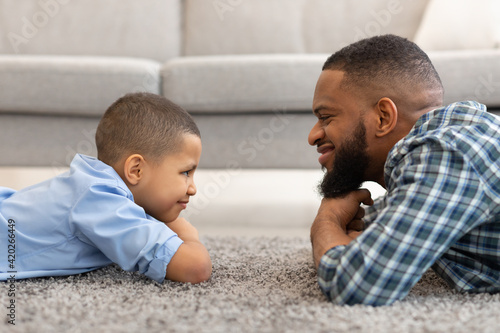 Canvas-taulu African Father And Son Lying On Floor At Home, Side-View