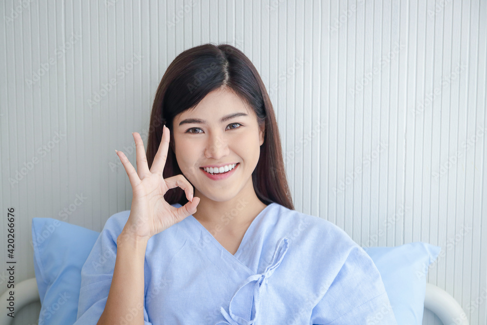 Female patient, beautiful smile, Asian Sitting in a hospital bed, thumbs up. Okay. The concept of medical services, health insurance. Female patient, beautiful smile, Asian Sitting in a hospital bed, thumbs up. Okay. The concept of medical services, health insurance.