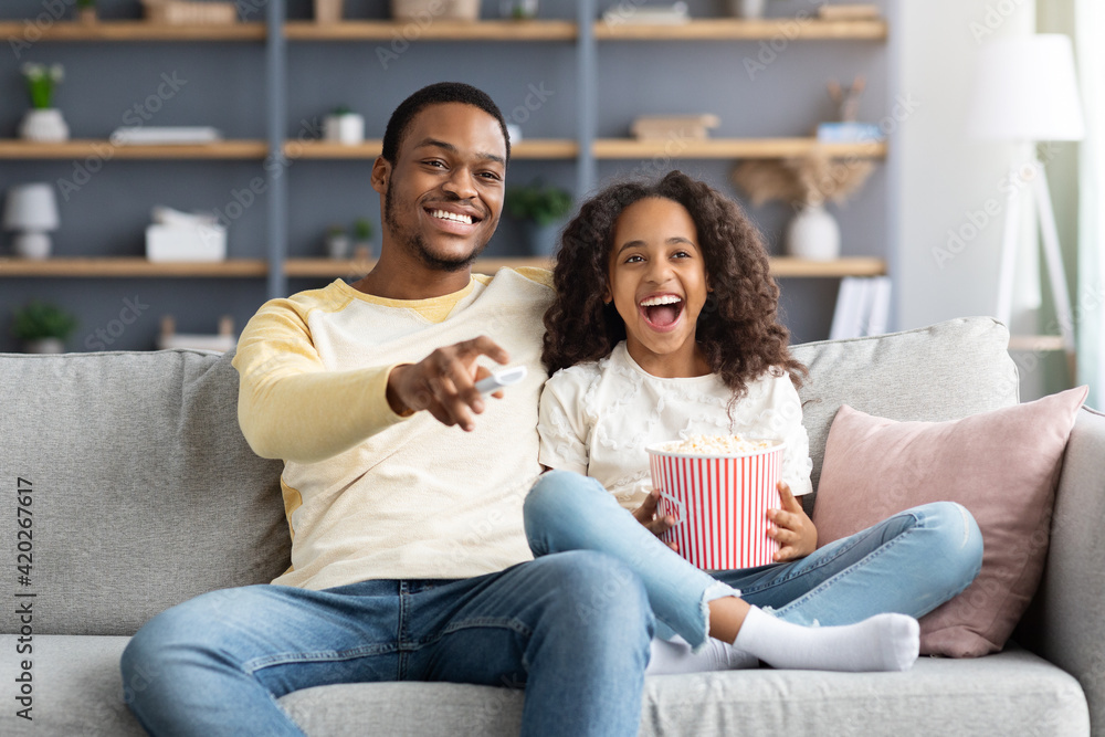 Happy black family father and daughter watching movie together