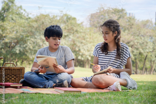A half-Thai Indian boy and a half-Thai-European girl friend learning outside of school in the park © ritfuse