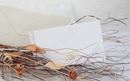 dry flowers on light background and a blank greeting card  invitation mockup with craft envelope
