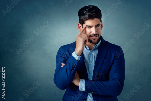 Portrait shot of handsome businessman looking thoughtfully while standing at isolated background