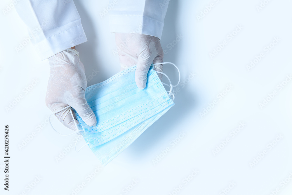 Fototapeta premium Doctor hands in medical gloves holding surgical protective mask isolated