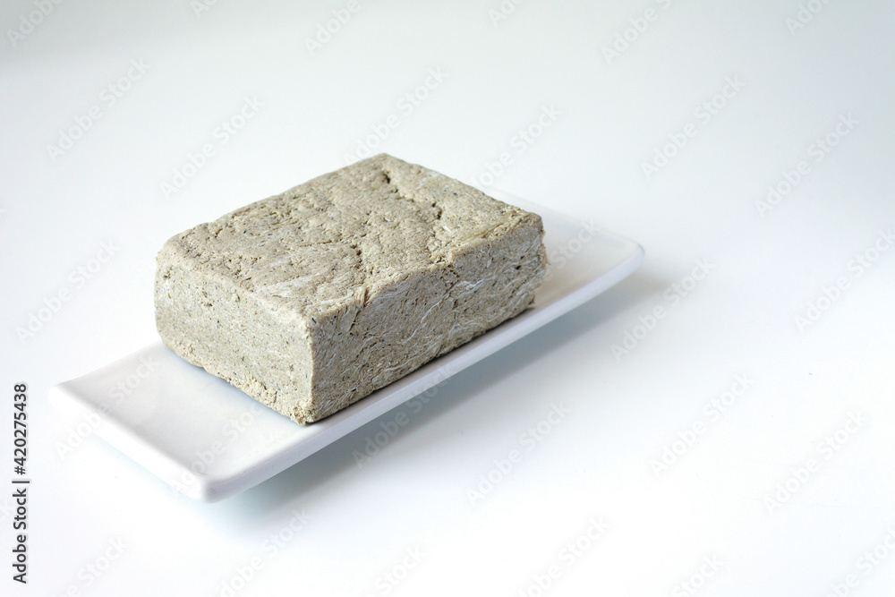 One piece of sunflower halva on a light background. Space for text One piece of sunflower halva on a light background. Space for text