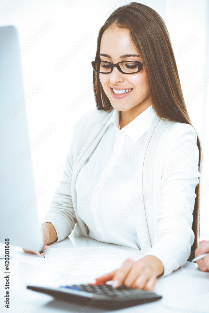 Young business woman and man sitting and working with computer and calculator in office. Bookkeeper checking balance or making finance report. Tax and audit concepts Young business woman and man sitting and working with computer and calculator in office. Bookkeeper checking balance or making finance report. Tax and audit concepts