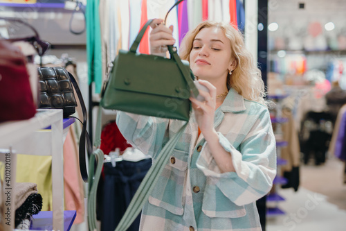 Woman chooses a green bag in the store before buying