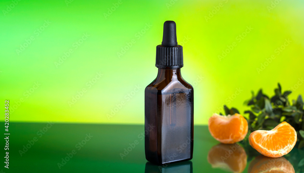 Mandarin oil. Brown bottle with a pipette on a green background. Mandarin oil. Brown bottle with a pipette on a green background.