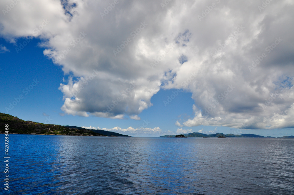 Tropical island on the ocean with white clouds and blue sky