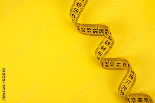 Yellow tape measure centimetric with copy space on yellow background photo