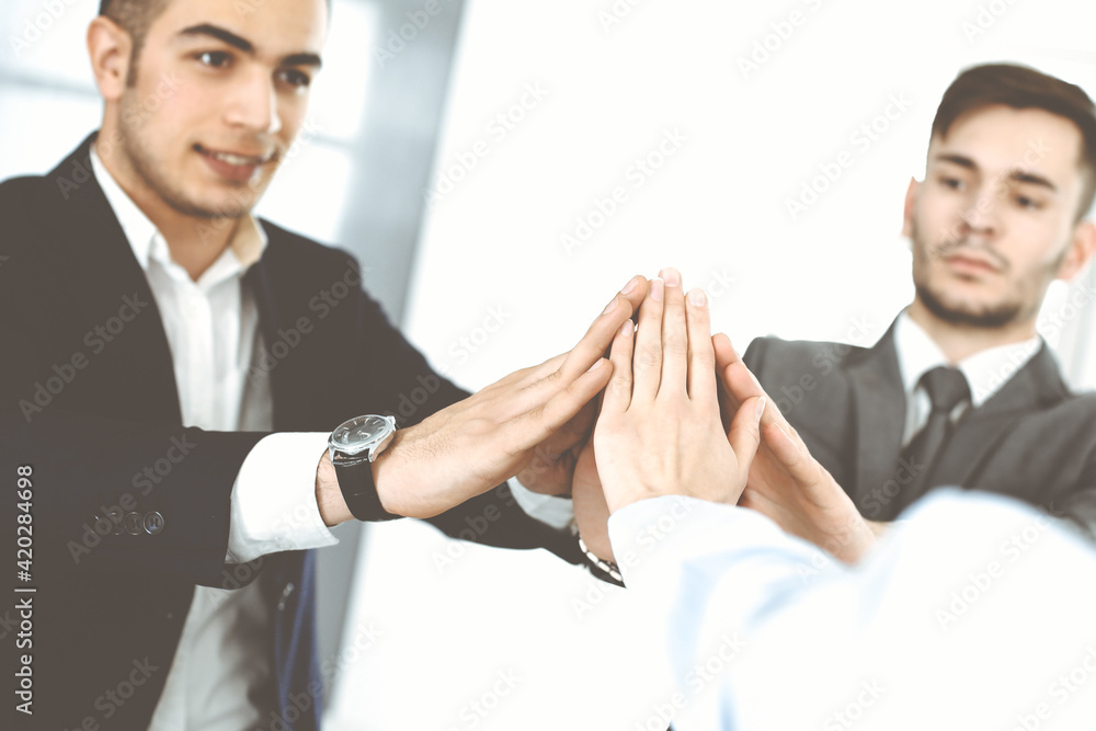 Business people group showing teamwork, joining hands and giving five to each other in modern office. Success concept Business people group showing teamwork, joining hands and giving five to each other in modern office. Success concept