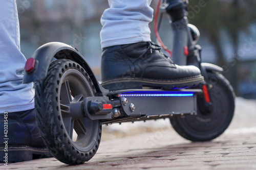 Electric scooter close-up. The guy stands near the electric scooter in the park. beautiful photo of a scooter in the park