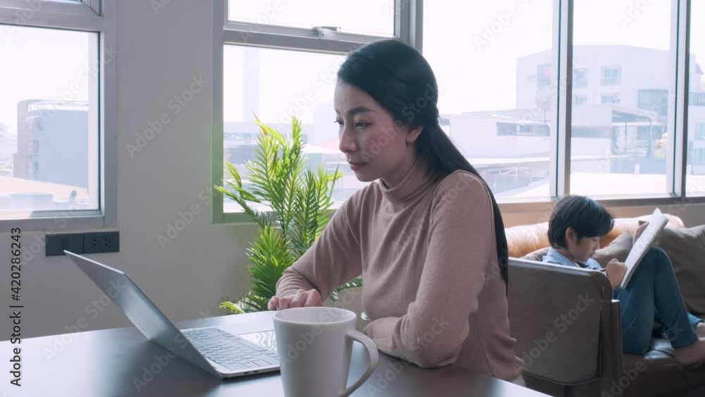 Mother using laptop work from home with son draws a picture on the back. Mother using laptop work from home with son draws a picture on the back.