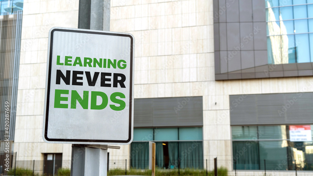 Fototapeta premium Learning never ends sign in a downtown city setting