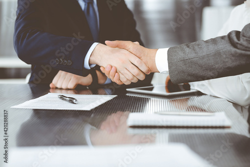 Fototapeta Naklejka Na Ścianę i Meble -  Handshake as successful negotiation ending, close-up. Unknown business people shaking hands after contract signing in modern office