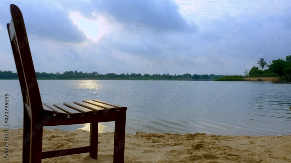 Concept of feeling of isolation and in despair presented by vacant wooden chair lying along silent river. 4k. Concept of feeling of isolation and in despair presented by vacant wooden chair lying along silent river. 4k.
