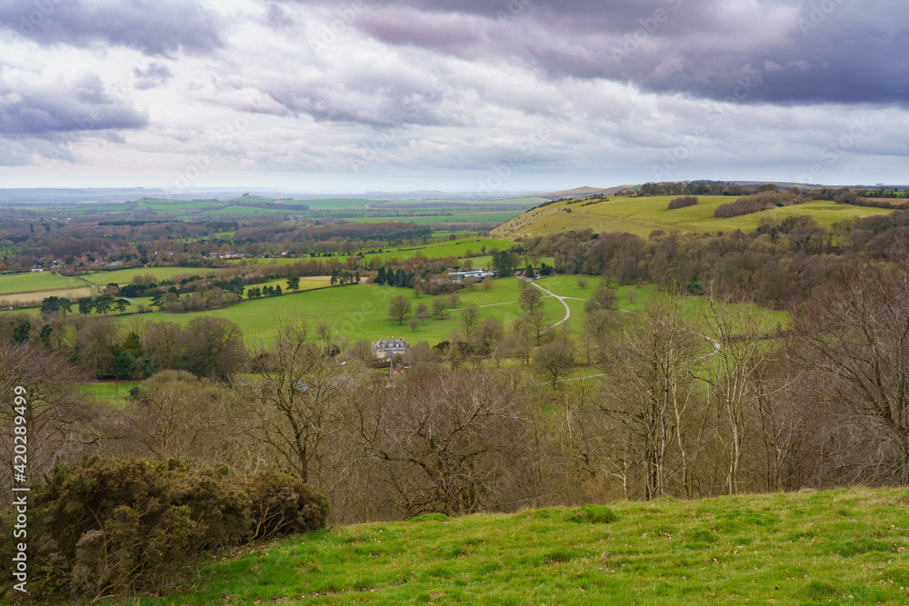 scenic view south west over Oare and across the Pewsey Vale valley with green pastures and a moody raincloud sky