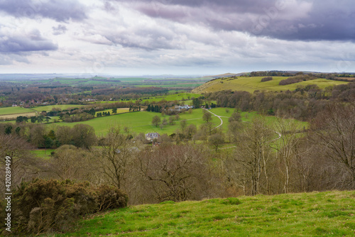 scenic view south west over Oare and across the Pewsey Vale valley with green pastures and a moody raincloud sky