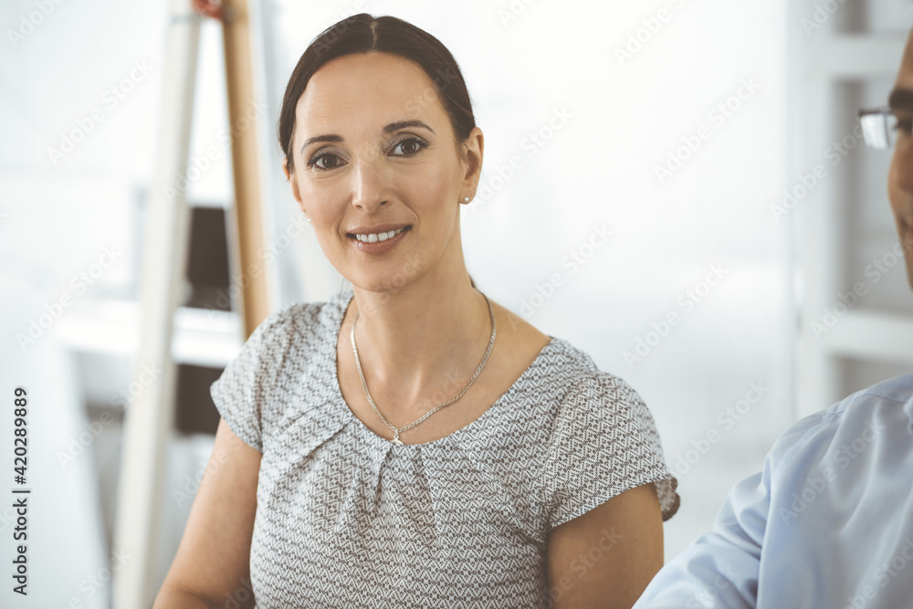 Businessman and hispanic business woman working with computer in a modern office. Group of diverse people. Teamwork, partnership and business concept Businessman and hispanic business woman working with computer in a modern office. Group of diverse people. Teamwork, partnership and business concept