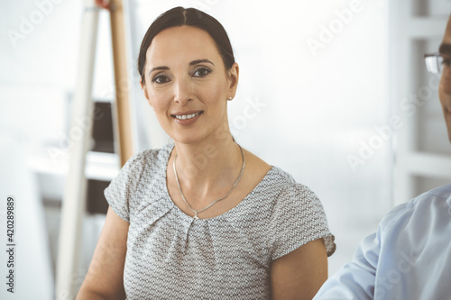 Businessman and hispanic business woman working with computer in a modern office. Group of diverse people. Teamwork, partnership and business concept