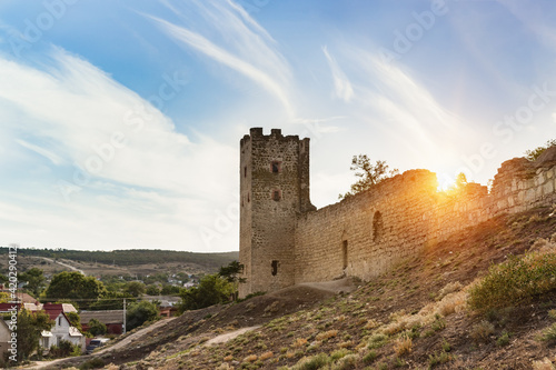 View from the shore of the Gulf of Feodosia to the defensive tower of Clement of the medieval fortress Kafa and the city of Feodosia. Sunset photo
