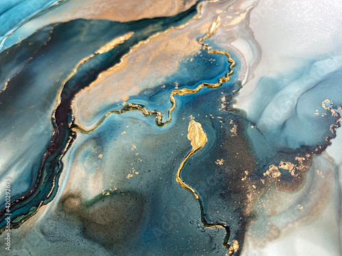 Abstract blue-green background with gold and beautiful smudges made with alcohol ink and golden acrylic. Fragment of art with turquoise texture resembles watercolor or aquarelle painting.