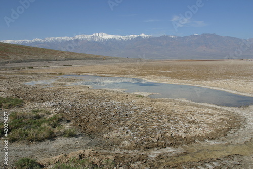 Death Valley Desert Landscape, California, With Salt Creek in Foreground Contrasted with the Snow capped Panamint Mountain Range in the Background photo