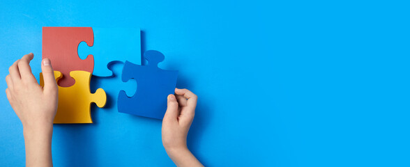 Top view hands of a autistic child arranging color puzzle symbol of awareness for autism spectrum disorder. Autism Awareness Day or month.