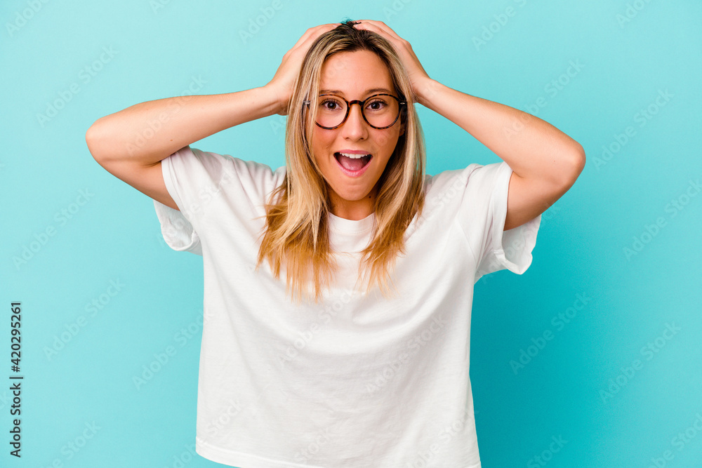 Young mixed race woman isolated on blue background screaming, very excited, passionate, satisfied with something. Young mixed race woman isolated on blue background screaming, very excited, passionate, satisfied with something.