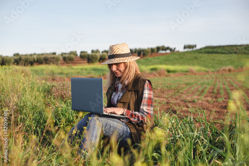 Female field engineer using computer in agricultural plantation. Integration of women in the field  agriculture and happy women concepts