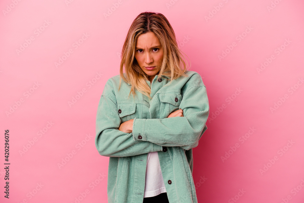 Young mixed race woman isolated on pink background frowning face in displeasure, keeps arms folded. Young mixed race woman isolated on pink background frowning face in displeasure, keeps arms folded.
