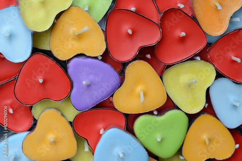 A random selection of coloured heart shaped candles, with one 'odd one out' coloured purple.